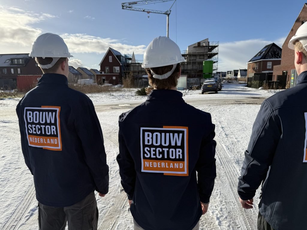 Vakmensen van Bouwsector Nederland met witte helm en logo op de rug op een besneeuwde bouwlocatie